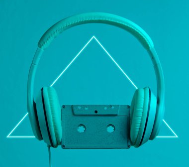 Retro dalga. Parlak üçgenli, neon ışıklı kulaklık ve ses kaseti. 80 'ler