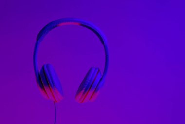 Gradyan mor neon ışığı olan klasik kablo kulaklıklar. Retro stil. Retro dalga. 80 'ler. Minimalist müzik konsepti.