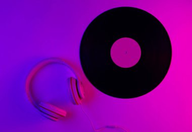 Retro tarzı müzik konsepti. Klasik kulaklıklar, gradyan pembe-neon ışıklı vinil plaklar. Popüler kültür. 80 'ler. Üst görünüm