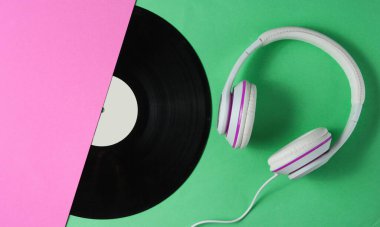 Retro tarzı müzik konsepti. Klasik kulaklıklar, renkli kağıt arka planda yarım vinil plak. Popüler kültür. 80 'ler. Üst görünüm