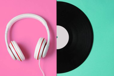 Retro tarzı müzik konsepti. Klasik kulaklıklar, renkli kağıt arka planda yarım vinil plak. Popüler kültür. 80 'ler. Üst görünüm