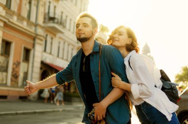 Genç, mutlu, şık aşıklar şehirde bir araba yakalıyorlar. Otostop konsepti