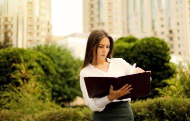 İş kadınıyım. Etek giyen çekici bir bayan yönetici ve şehir manzarasının arka planında dokümanların olduğu bir dosya tutan bir bluz. Hepsi iş hayatında.