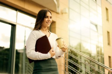 İş merkezinden çıkarken ve dışarıda kahve içerken merdivenlerden inerken bluz ve etek giyen kasıtlı bir iş kadını.