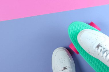 Plastik kruvazör tahtasındaki beyaz spor ayakkabılar. Pastel renk arkaplanı. Üst görünüm