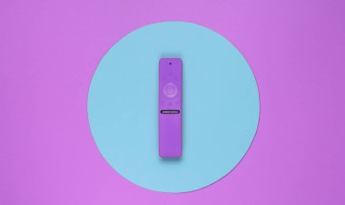 Pembe arka planda, mavi daireli, modern televizyon kumandası. Üst görünüm