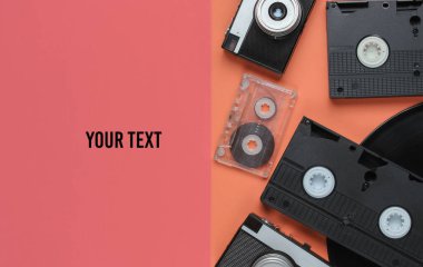 Retro nesneler. Retro kamera, vinil kayıt, video kasetler, renkli arka planda fotokopi alanı olan ses kaseti. 80 'ler. Üst görünüm