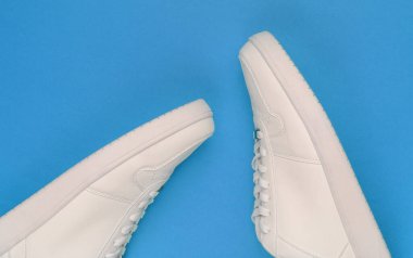 Mavi arka planda beyaz spor ayakkabılar. Gençlik hipster konsepti. Üst görünüm