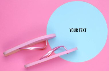 Fotokopi alanı için mavi pastel daire ile pembe arka planda pembe parmak arası terlikler. Plaj konsepti üzerine minimalist bir tatil. Yaz zamanı. Üst görünüm