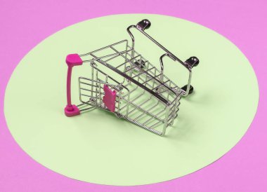 Pembe arka planda sarı pastel daireli alışveriş arabası. Minimalist alışveriş konsepti, alışveriş koliği.