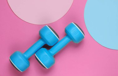 Pembe arka planda plastik halterler ve fotokopi alanı için mavi pastel daireler. Üst Manzara. Minimalist spor konsepti. Üst görünüm