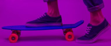 Gençlik hipster konsepti. Kotlu kadın bacakları ve kruvazörde mor neon ışıklı spor ayakkabılar. Yaz eğlencesi