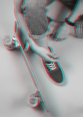 Gençlik hipster konsepti. Kotlu ve spor ayakkabılı kadın bacakları beyaz arka planda kruvazör tahtasıyla oturuyor. Arıza efekti