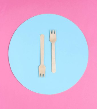 Pembe arka planda mavi daireli çevre dostu ahşap çatallar. Üst görünüm, minimalizm