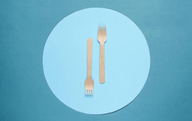 Mavi arka planda mavi daireli çevre dostu ahşap çatallar. Üst görünüm, minimalizm