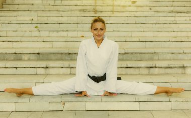Siyah kuşaklı beyaz kimonolu çekici bir kadın. Spor kadın dışarıda merdivenlerde sicim içinde oturuyor. Dövüş sanatları