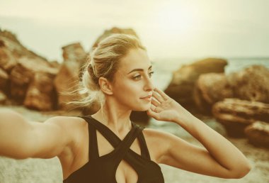 Vahşi sahilde mayo giymiş çekici bir sarışının selfie portresi.