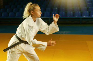 Beyaz kimonolu, siyah kuşaklı dövüş sanatları ustası içeride ayakta duruyor. Spor portresi