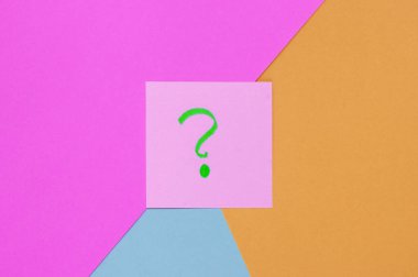 Renkli arkaplanda soru işaretleri olan bir not kağıdı parçası. Üst Manzara. Minimalizm