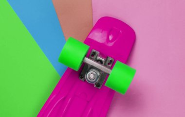 Renkli arka planda plastik mini kruvazör tahtası. Pastel renk eğilimi. Yaz eğlencesi. Gençlik minimalist konsepti. Üst görünüm