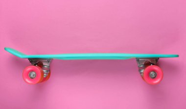 Pembe arka planda plastik mini kruvazör tahtası. Pastel renk eğilimi. Yaz eğlencesi. Gençlik minimalist konsepti. Üst görünüm