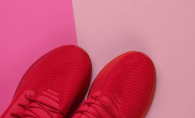 Pembe arka planda koşmak için şık kırmızı spor ayakkabılar. Üst görünüm