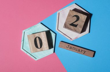 Ahşap blok takvimine göre tarih Ocak 02, pembe mavi arka plan. Üst görünüm