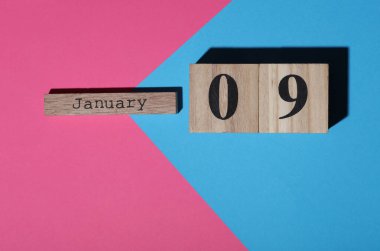 Ahşap blok takvimine göre tarih 09 Ocak, pembe mavi arka plan. Üst görünüm