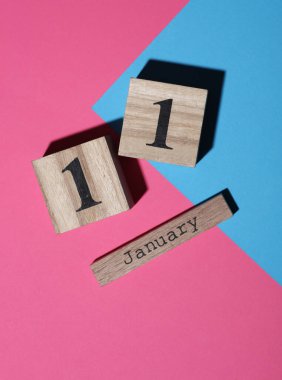 Ahşap blok takvimine göre tarih 11 Ocak, pembe mavi arka plan. Üst görünüm