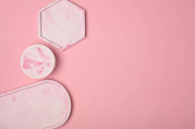 Pembe arka planda farklı şekillerde dekoratif pembe alçı tepsiler. Kozmetik veya mücevher için mum düzenleyicileri anlamına geliyor. Üst görünüm
