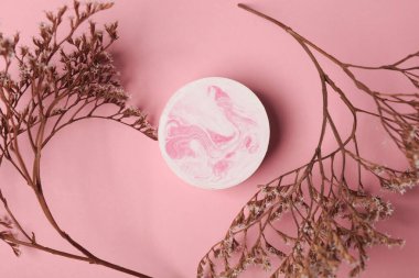 Pembe arka planda kuru çiçekli sıva podyum. Üst görünüm