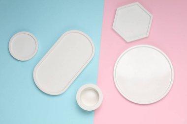 Mavi pembe pastel arka planda farklı şekillerde dekoratif beyaz alçı tepsiler. Kozmetik veya mücevher için mum düzenleyicileri anlamına geliyor. Üst görünüm