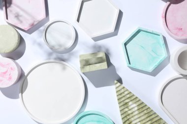 Beyaz arka planda gölgeli farklı şekillerde dekoratif pembe alçı tepsiler. Kozmetik veya mücevher için mum düzenleyicileri anlamına geliyor. Üst görünüm