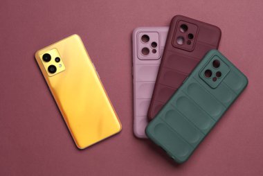 Burgonya arka planında koruyucu kılıfları olan akıllı telefon. Üst görünüm