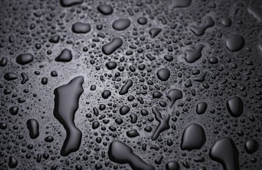 Siyah bir yüzeye düşen su damlaları