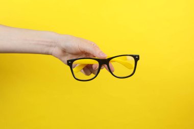 Sarı arka planda el ele tutuşan gözlükler.