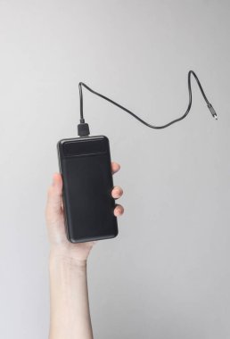 Gri arka planda siyah taşınabilir güç bankası var.