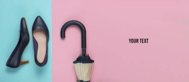 Klasik yüksek topuklu ayakkabılar, pembe mavi arka planda şemsiye ve fotokopi alanı. Minimalizm moda kavramı. Üst görünüm