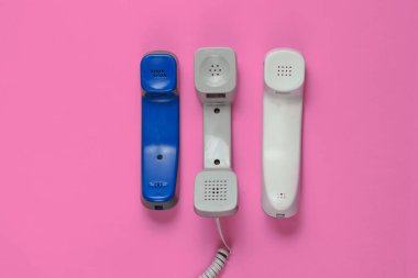 Pembe arka planda üç ofis telefonu. Üst görünüm