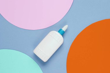 Mavi kağıda bir şişe tutkal ve daireler. Üst görünüm