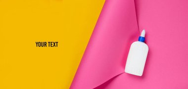 Renkli bir stüdyo kağıdının üzerine bir şişe yapıştırıcı ve metin için yer. Üst görünüm