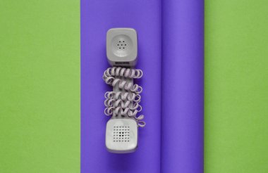 Mor yeşil kağıt arka planda kablolu cep telefonu. 