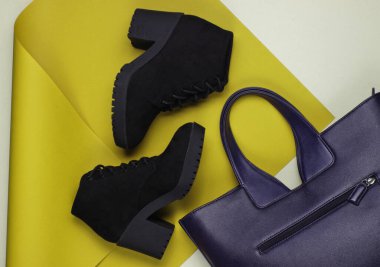 Katlanmış kağıt arka planda siyah süet botlar ve deri çanta. Minimalist moda hala hayattadır. Düz yatıyordu. Üst görünüm