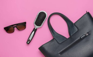 Pembe arka planda yassı kadın aksesuarları. Çanta, güneş gözlüğü, tarak. Üst görünüm