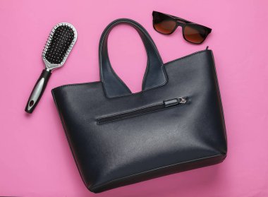 Pembe arka planda yassı kadın aksesuarları. Çanta, güneş gözlüğü, tarak. Üst görünüm