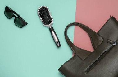 Pembe arka planda yassı kadın aksesuarları vardı. Çanta, güneş gözlüğü, tarak. Üst görünüm