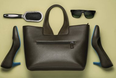 Sarı arka planda düz stil kadın aksesuarları vardı. Çanta, yüksek topuklu ayakkabı, güneş gözlüğü, tarak. Üst görünüm