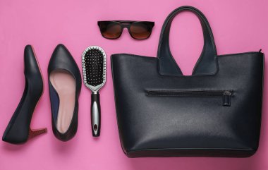 Pembe arka planda yassı kadın aksesuarları. Çanta, yüksek topuklu ayakkabı, güneş gözlüğü, tarak. Üst görünüm