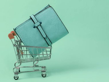 Minimalist alışveriş konsepti. Mavi pastel arka planda cüzdanı olan mini alışveriş arabası.