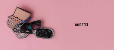 Minimalist alışveriş konsepti. Pembe pastel arka planda kadın aksesuarları olan mini alışveriş sepeti. Boşluğu kopyala